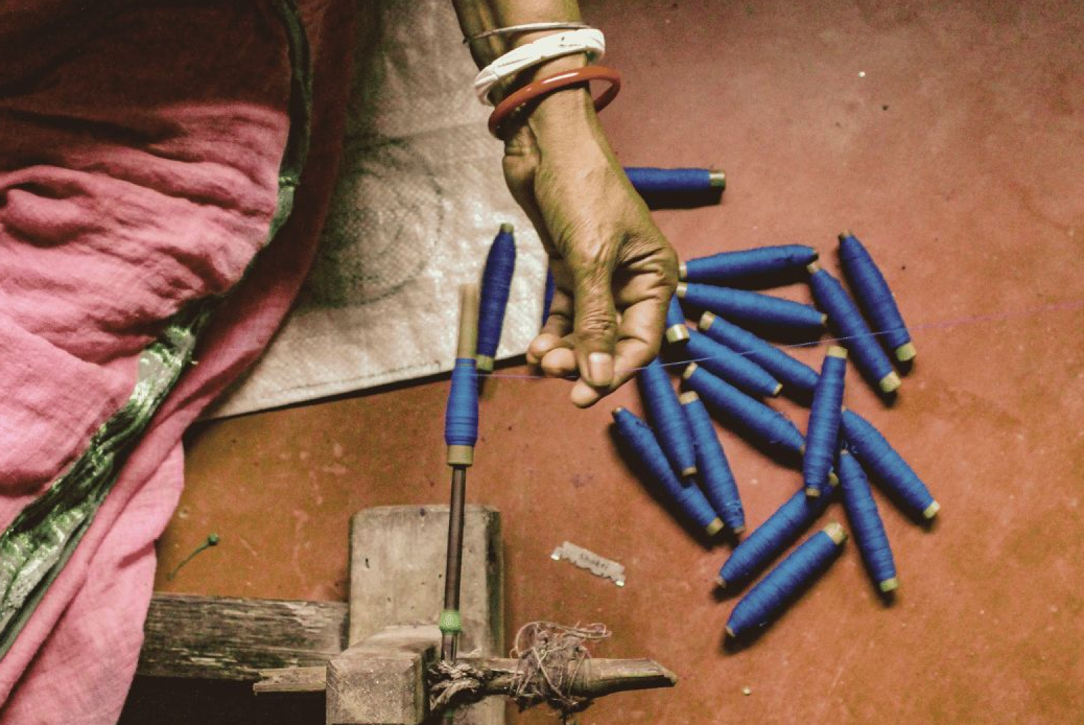 Artisan winding blue yarn onto bobbins for handloom saree weaving