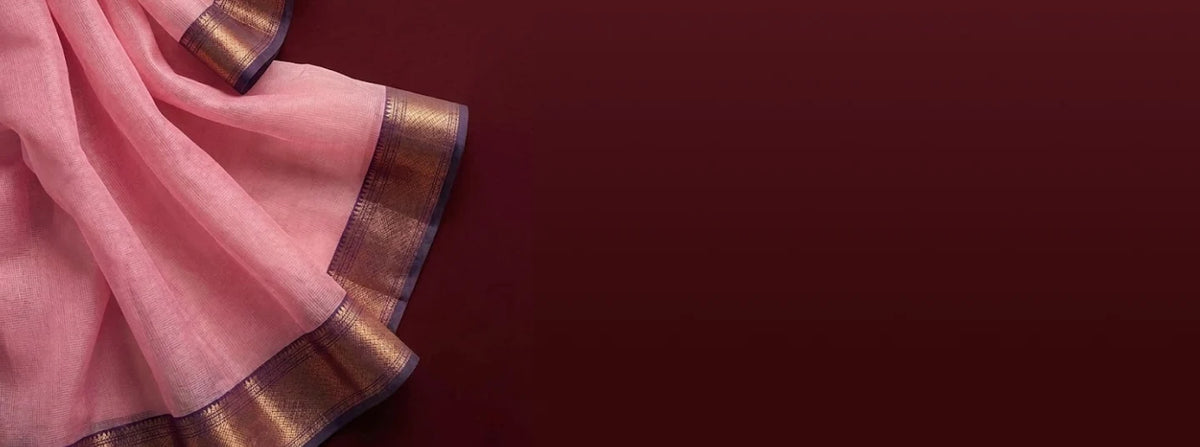 Pink saree with metallic woven border draped against a maroon background