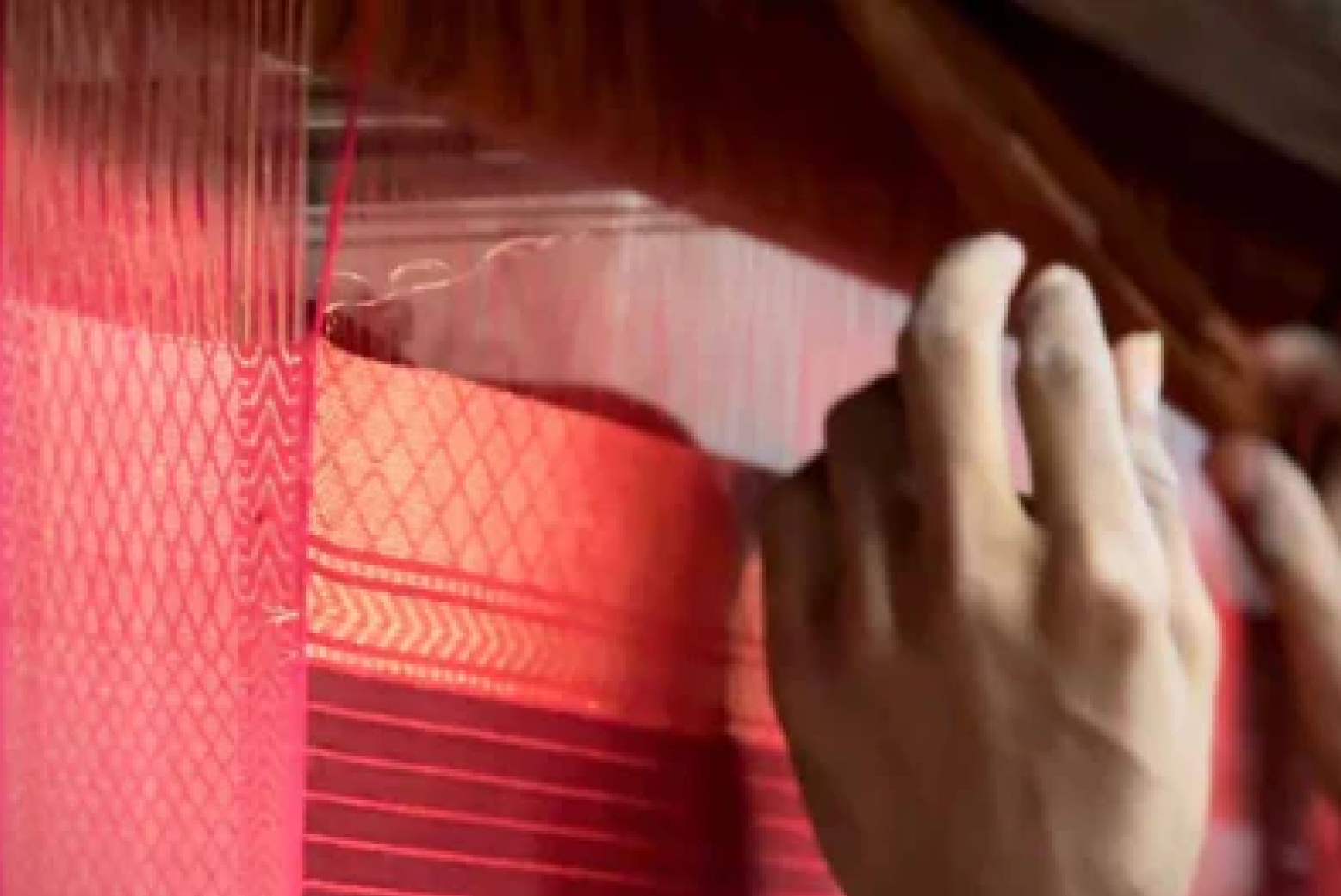 Red patterned fabric being woven on a traditional handloom