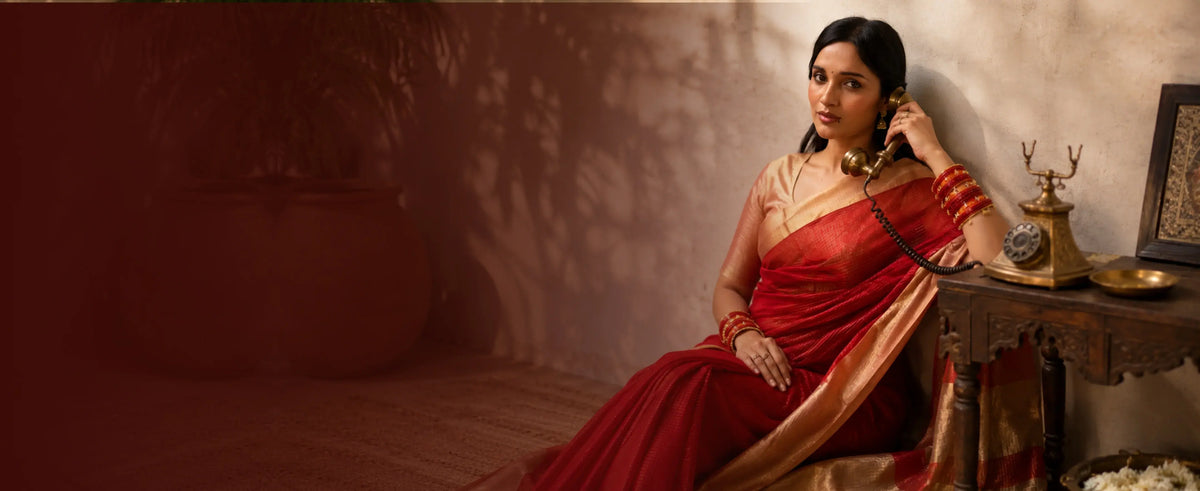 Woman wearing a red saree with gold border speaking on a vintage telephone